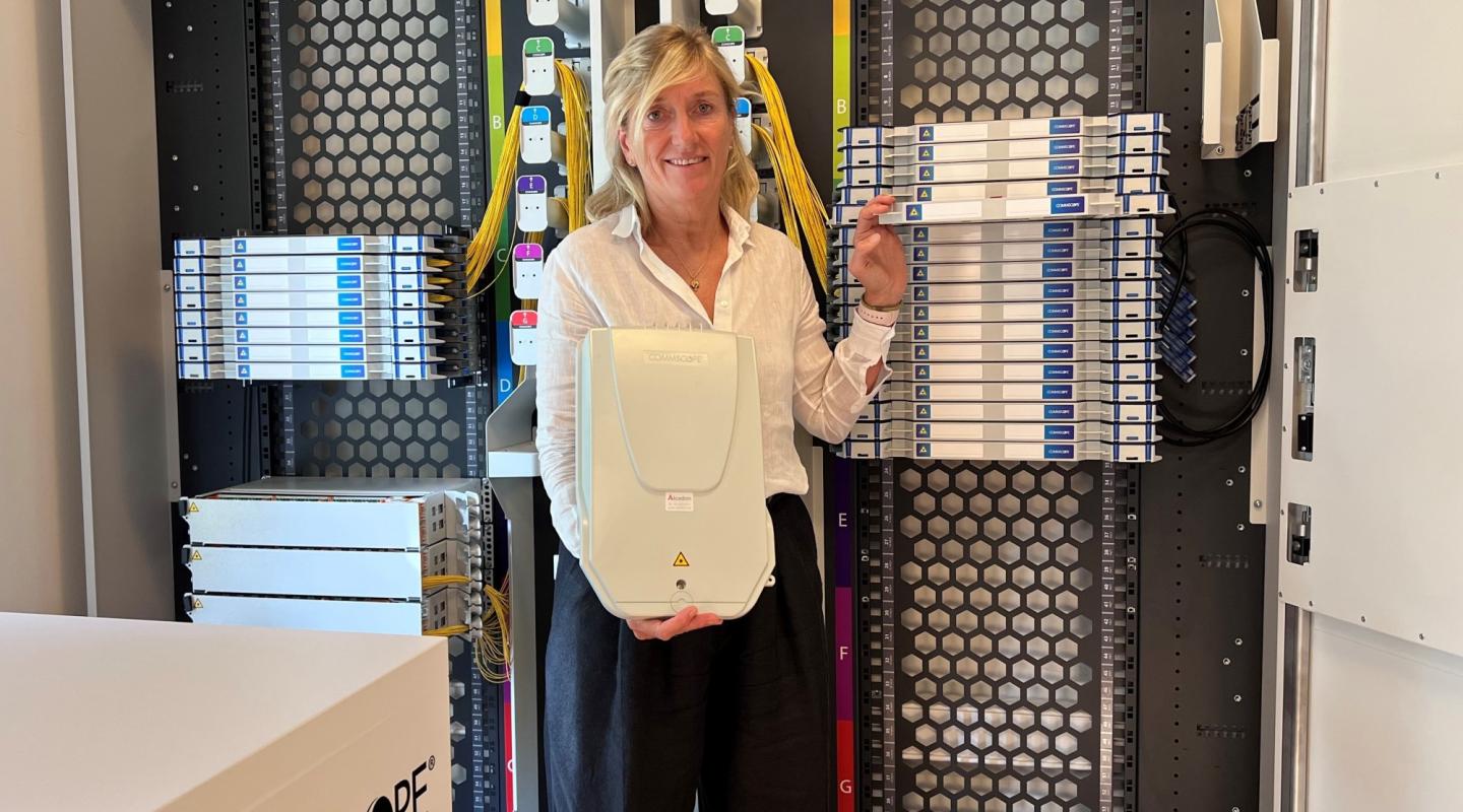 Susanne Stengade is proudly showcasing a FACT optical distribution frame (ODF) and a BUDI wall-mounted fiber enclosure.