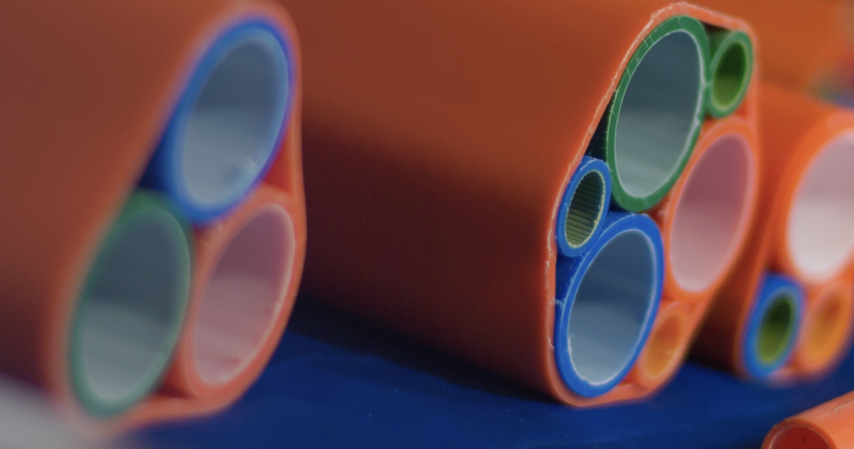 Close-up view of orange multi-duct conduits containing several inner microducts in various colors (blue, green, pink, etc.), typically used for fiber optic cable installations