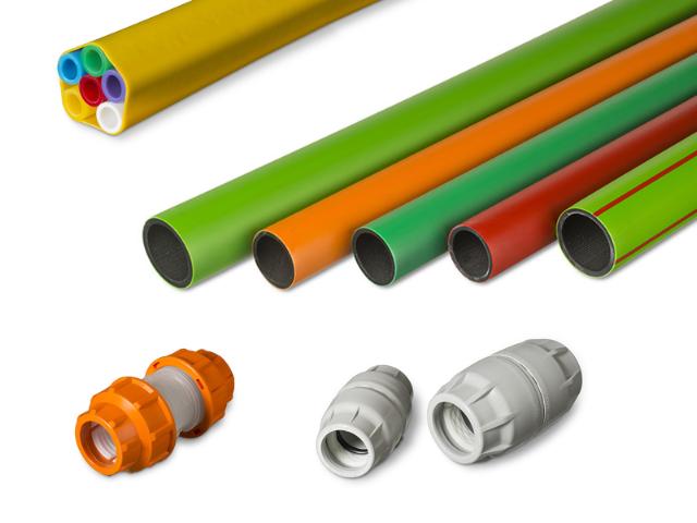 Assortment of colored microducts and accessories including single and bundled microducts in yellow, orange, green, and red, as well as various types of microduct connectors in orange and grey. Used for fiber optic cable installations.