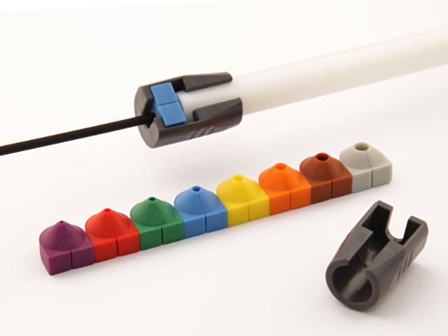 Set of colorful Filoform plastic inserts for cable identification, displayed in a row with one inserted into a cable holder mounted on a white tube. Used for organizing and color-coding fiber optic or microduct cables.