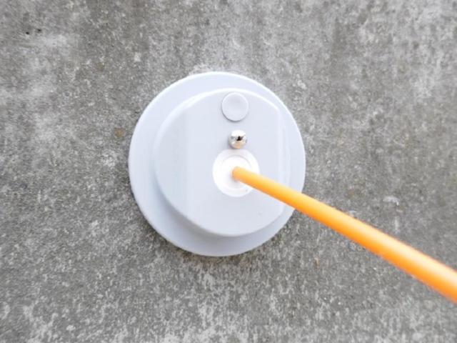 Close-up of a Filoform round wall-mounted cable entry seal with a single orange cable passing through, installed in a concrete wall for sealing and protection.