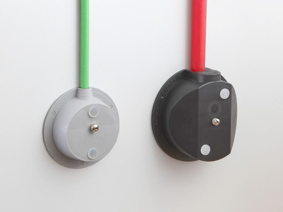 Two wall-mounted Filoform cable sealing systems, one gray with a green cable and one black with a red cable, designed for secure and airtight cable entries.