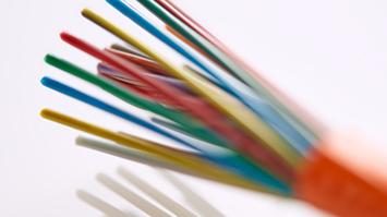 Close-up of a fiber optic cable with multiple exposed color-coded fiber strands extending from an orange sheath, shown against a white background