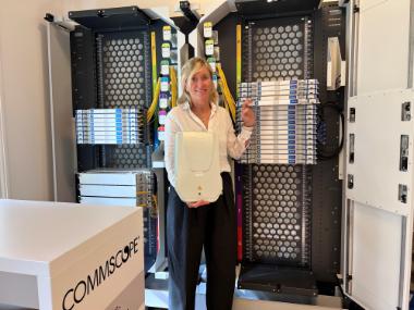 Susanne Stengade is proudly showcasing a FACT optical distribution frame (ODF) and a BUDI wall-mounted fiber enclosure.
